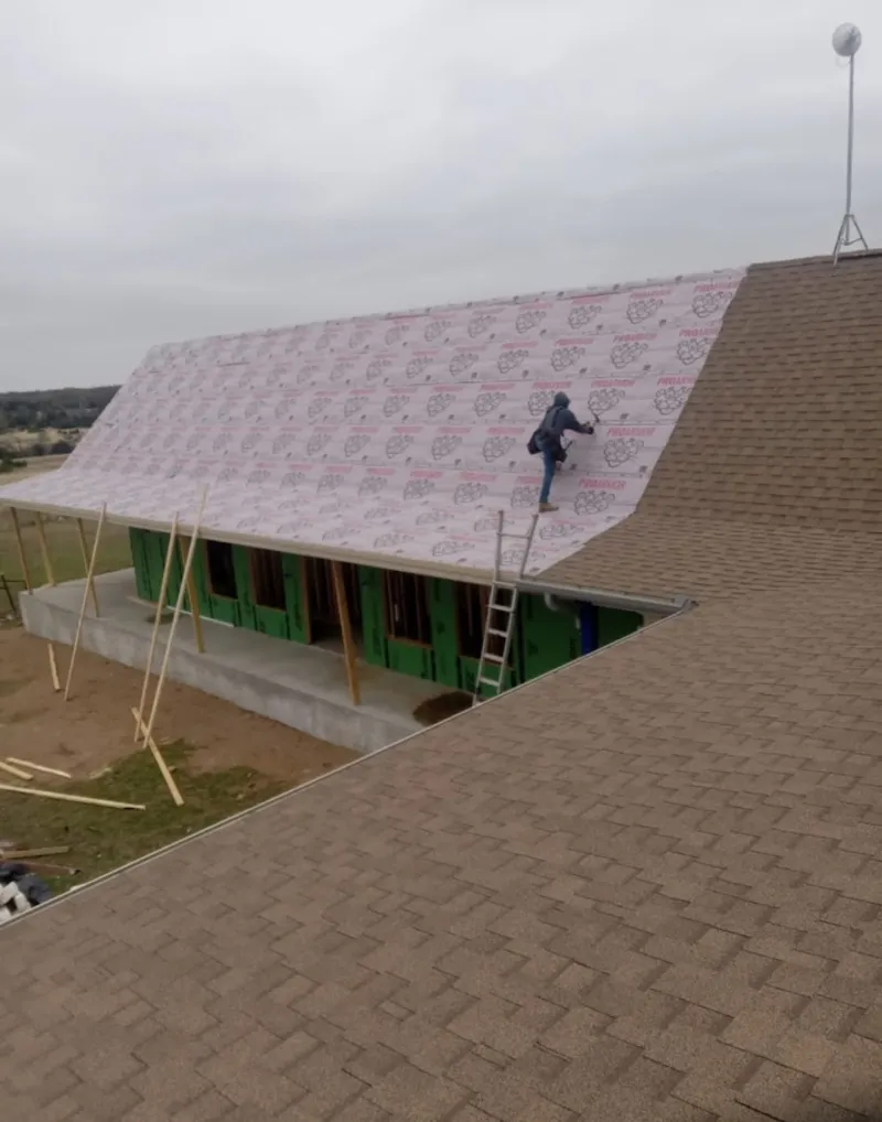 Worker preparing underlayment for a metal roof installation in Doffing